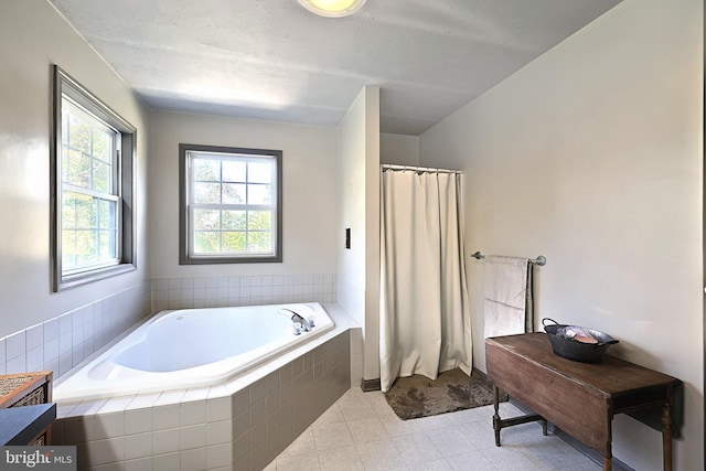 bathroom featuring a relaxing tiled tub and tile patterned flooring