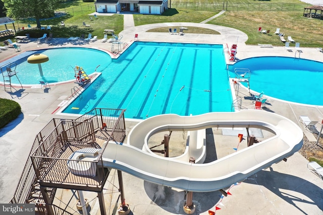 view of swimming pool with a water slide, a patio, and a yard