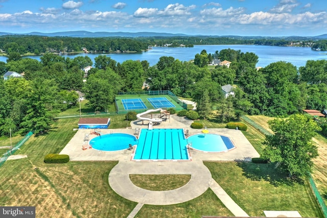 view of pool featuring a water view, a lawn, and a patio area