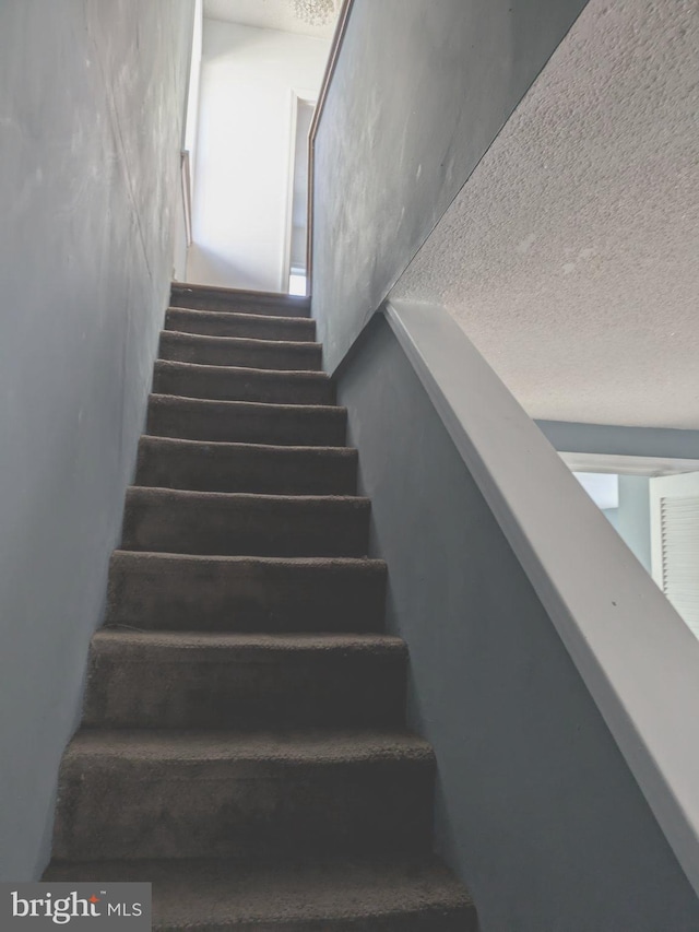 staircase with a textured ceiling