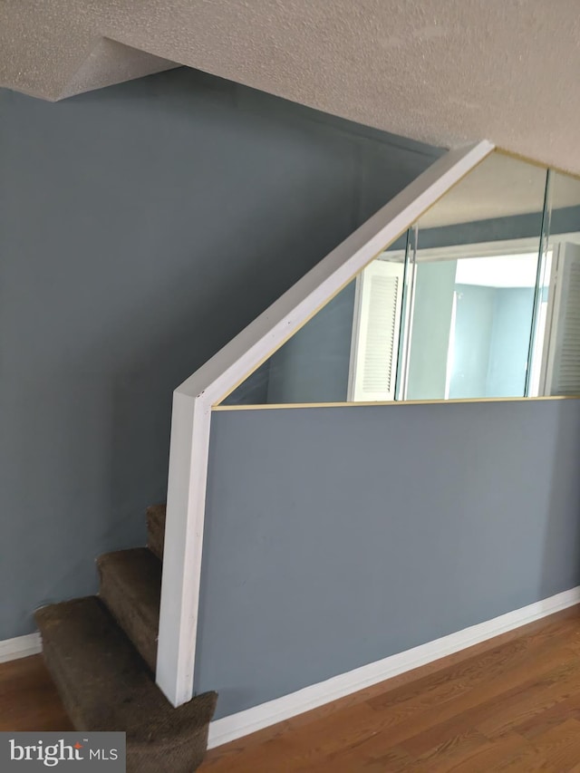 staircase featuring hardwood / wood-style flooring, a textured ceiling, and vaulted ceiling