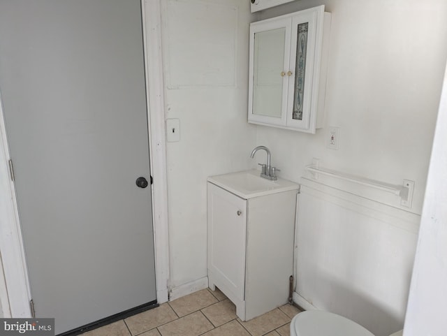 half bathroom featuring tile patterned floors, toilet, and vanity
