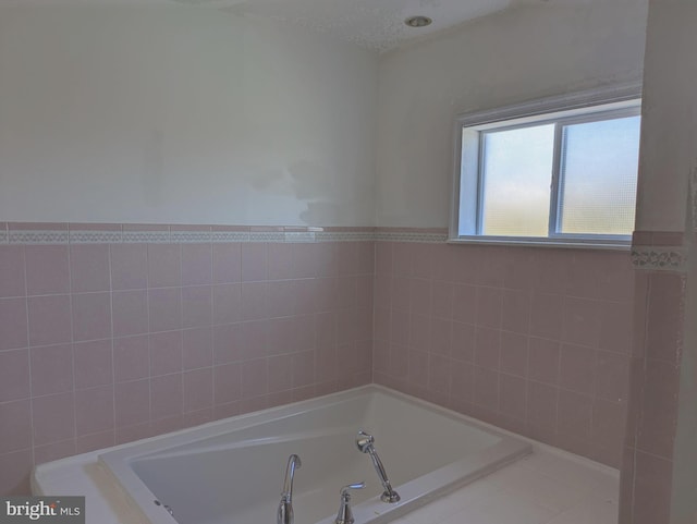 bathroom with a tub, tile walls, and a textured ceiling