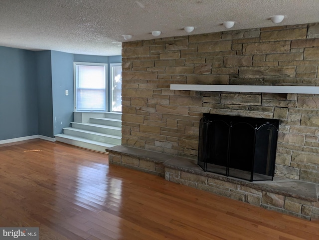 interior details with a stone fireplace, hardwood / wood-style floors, and a textured ceiling