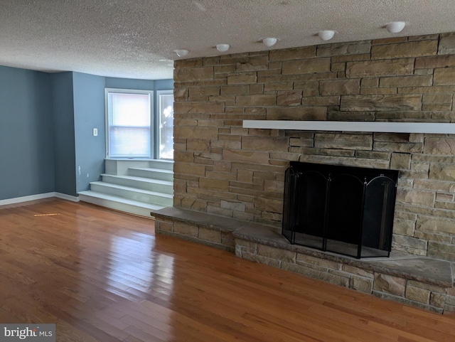 interior details with a fireplace, a textured ceiling, baseboards, and wood finished floors