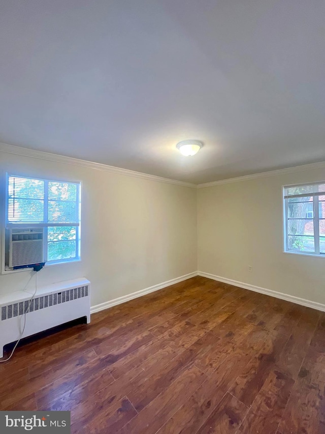 spare room with cooling unit, crown molding, dark hardwood / wood-style flooring, and radiator