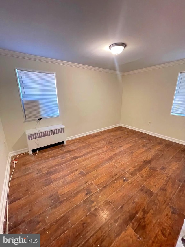 empty room featuring ornamental molding, hardwood / wood-style floors, and radiator heating unit