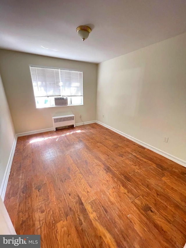 empty room featuring radiator and hardwood / wood-style floors