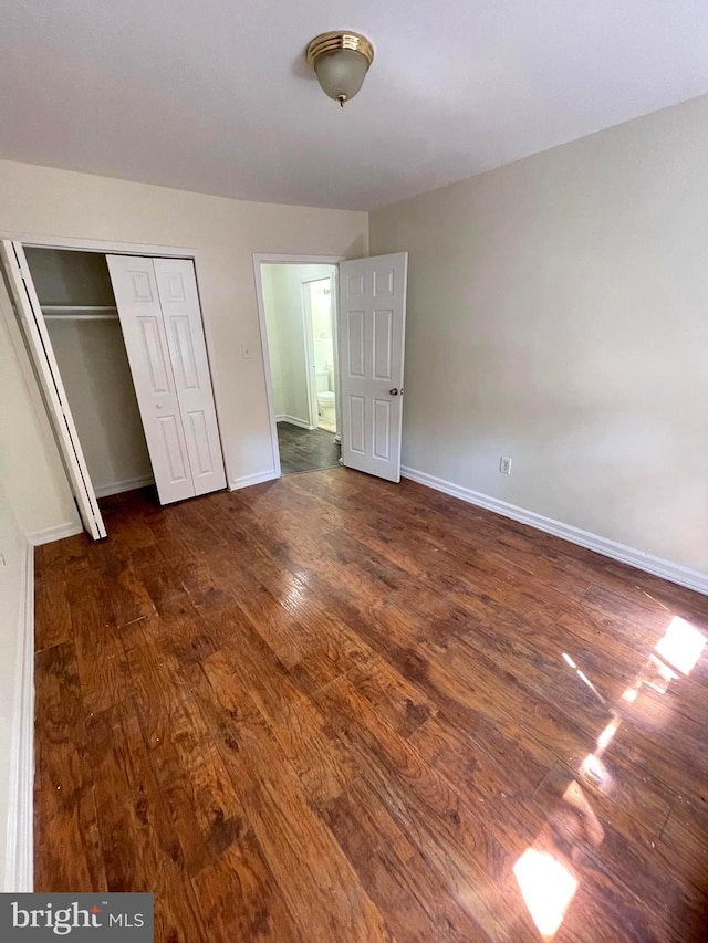 unfurnished bedroom with a closet and dark hardwood / wood-style floors