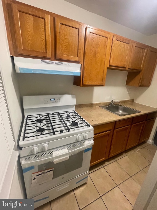 kitchen with stainless steel range with gas cooktop, sink, and light tile patterned floors