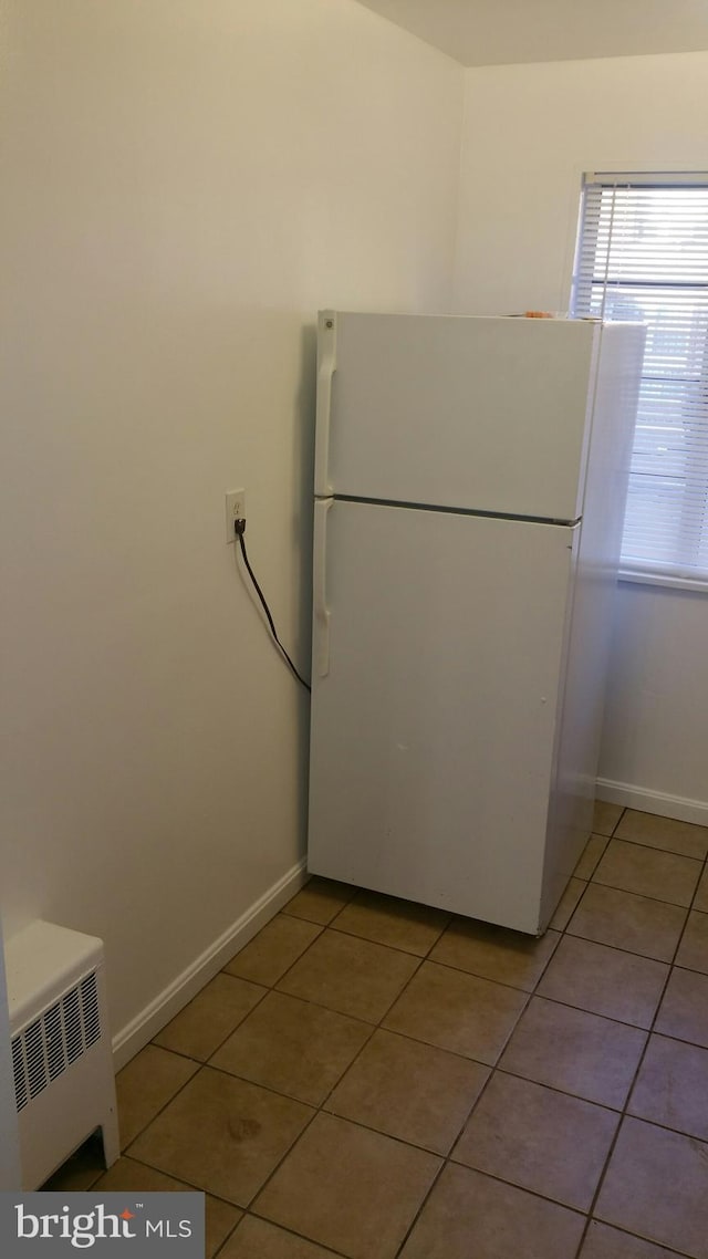 kitchen featuring light tile patterned flooring, white refrigerator, and radiator heating unit