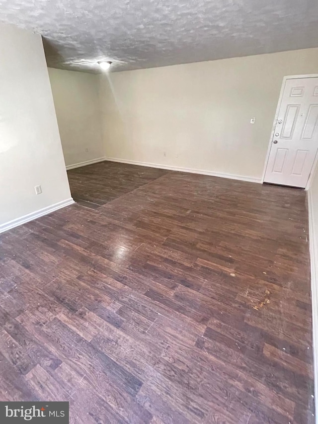 spare room featuring dark wood-type flooring and a textured ceiling