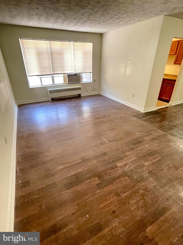 unfurnished living room with dark wood-type flooring, radiator heating unit, and a textured ceiling