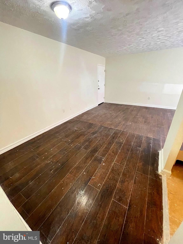 spare room with dark hardwood / wood-style floors and a textured ceiling