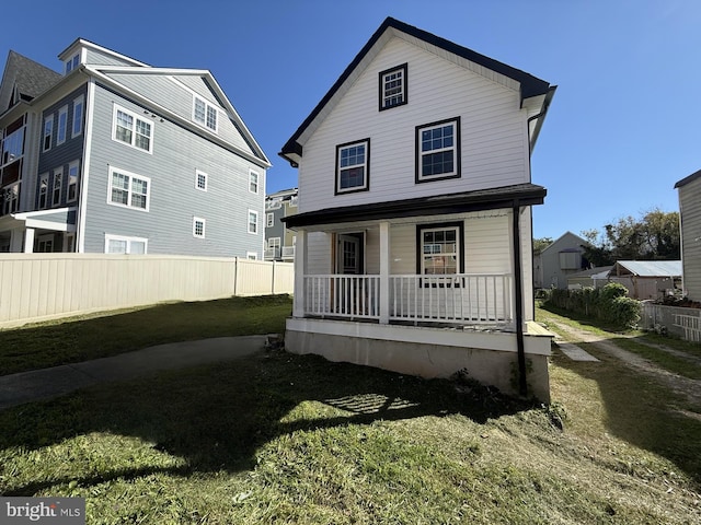 back of house featuring a lawn and covered porch