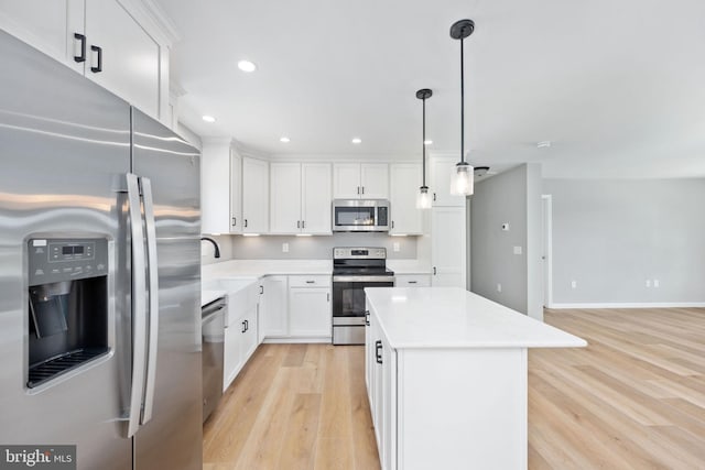 kitchen with a center island, pendant lighting, white cabinetry, light hardwood / wood-style flooring, and appliances with stainless steel finishes