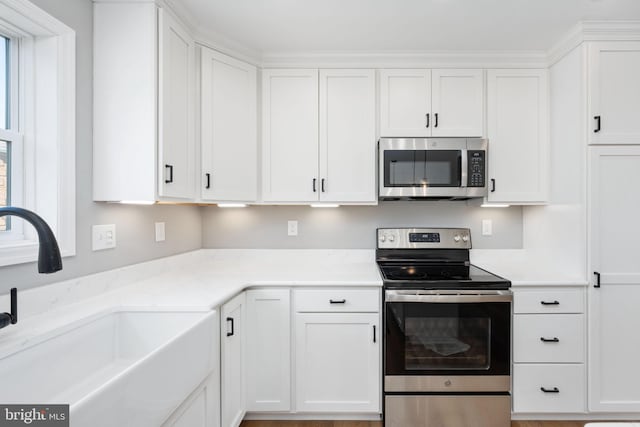 kitchen featuring white cabinets, appliances with stainless steel finishes, plenty of natural light, and sink