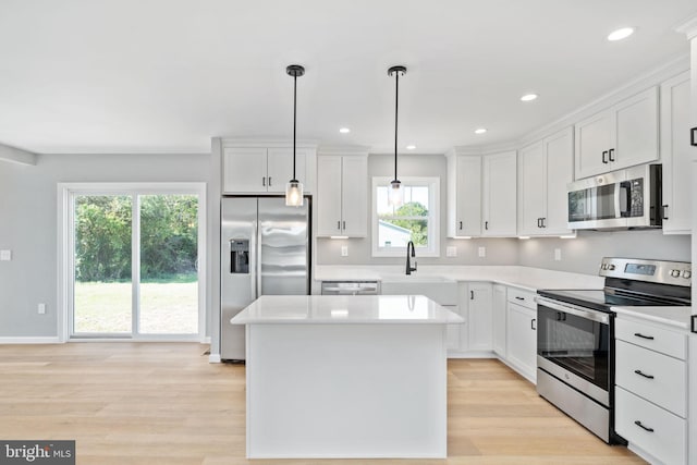 kitchen with decorative light fixtures, stainless steel appliances, white cabinets, and a wealth of natural light