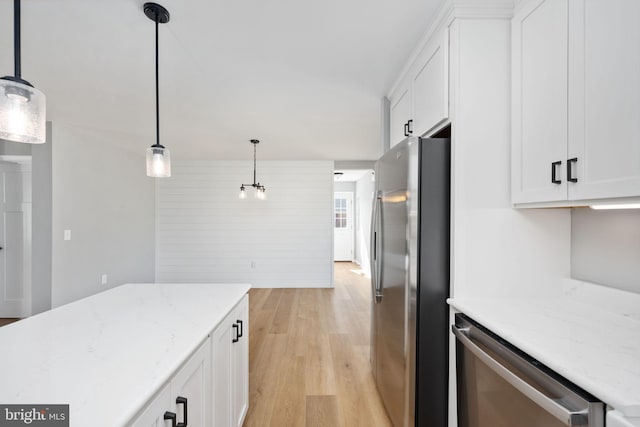 kitchen with decorative light fixtures, white cabinets, stainless steel appliances, and light hardwood / wood-style flooring