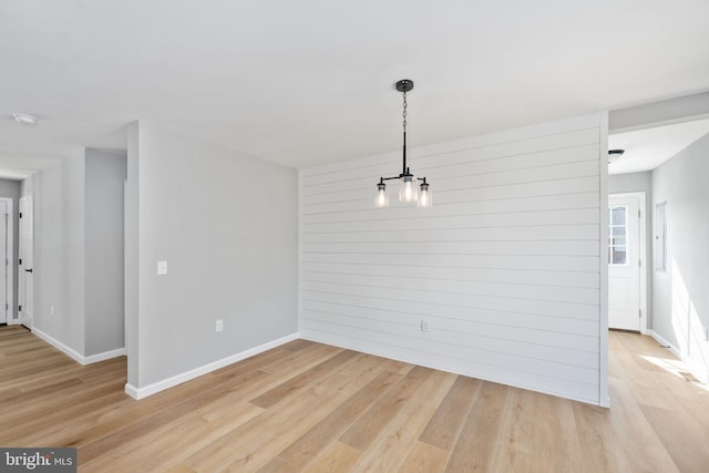 unfurnished dining area with light hardwood / wood-style flooring and wood walls