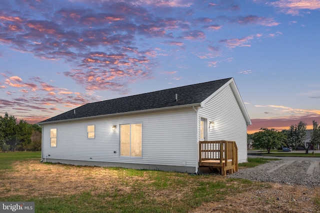 property exterior at dusk featuring a yard and a wooden deck