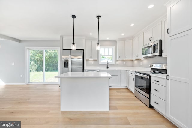 kitchen featuring pendant lighting, a wealth of natural light, stainless steel appliances, and white cabinets