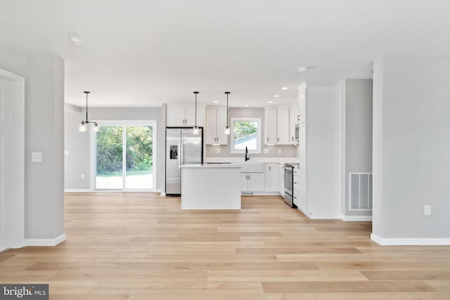 kitchen with stainless steel appliances, pendant lighting, a kitchen island, and a wealth of natural light