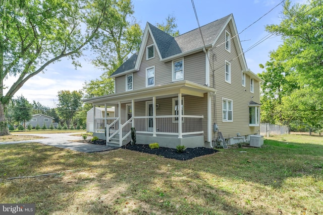 view of front of property featuring a front yard, central AC, and covered porch