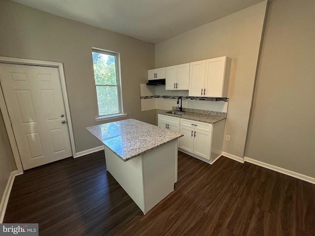 kitchen featuring white cabinetry, a kitchen island, light stone countertops, dark hardwood / wood-style flooring, and sink