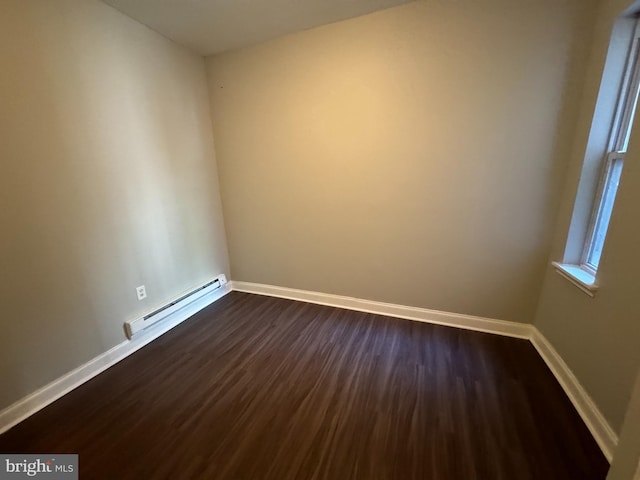 unfurnished room with dark hardwood / wood-style floors and a baseboard heating unit