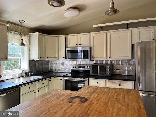 kitchen featuring wooden counters, decorative light fixtures, stainless steel appliances, and sink