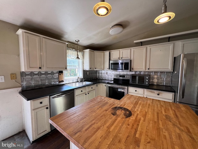 kitchen with butcher block counters, sink, hanging light fixtures, lofted ceiling, and appliances with stainless steel finishes