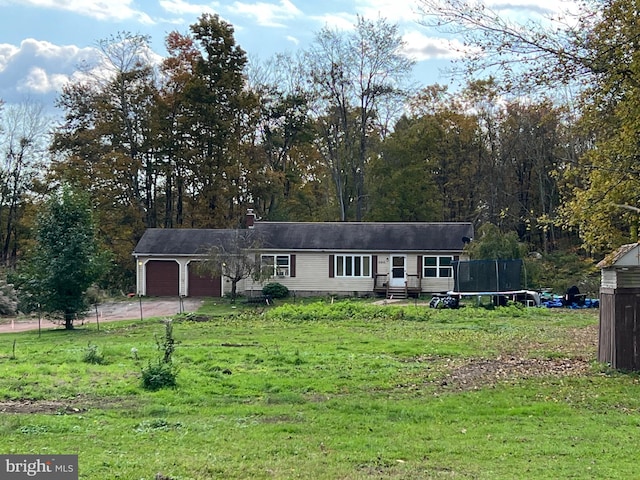 view of front facade featuring a front yard, a trampoline, and a garage