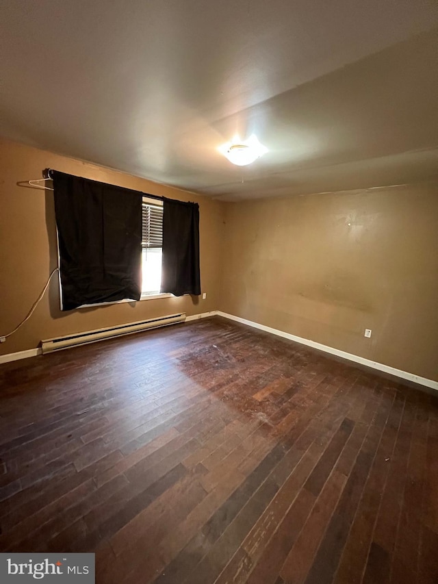 empty room with dark wood-type flooring and a baseboard heating unit