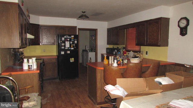 kitchen featuring black appliances, dark brown cabinets, dark hardwood / wood-style floors, and extractor fan