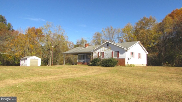 ranch-style home with a storage shed and a front lawn