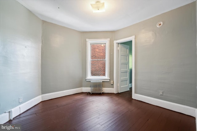 unfurnished room featuring radiator heating unit and dark hardwood / wood-style floors