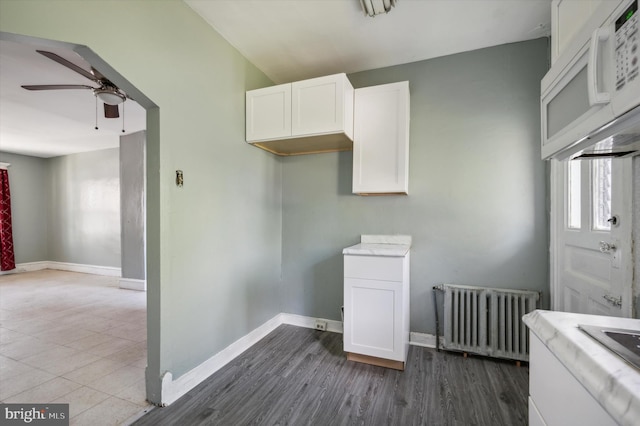 laundry area with radiator heating unit, hardwood / wood-style floors, and ceiling fan