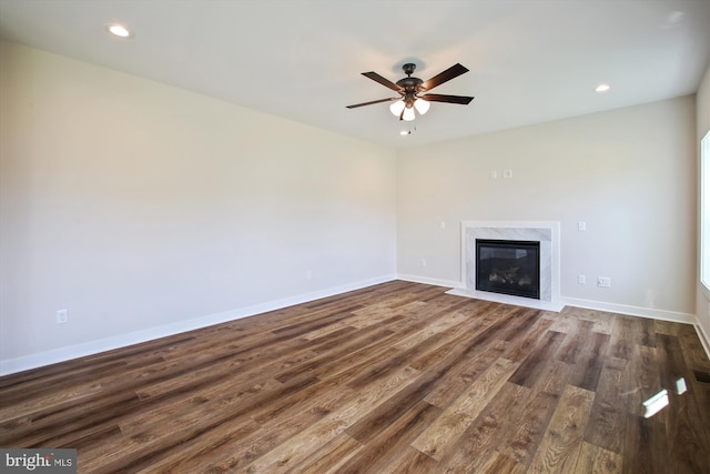 unfurnished living room featuring ceiling fan, a fireplace, dark wood-type flooring, recessed lighting, and baseboards