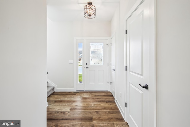 entryway featuring wood finished floors, baseboards, and stairway
