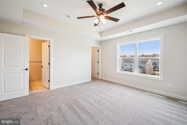 unfurnished bedroom with recessed lighting, a tray ceiling, baseboards, and carpet floors