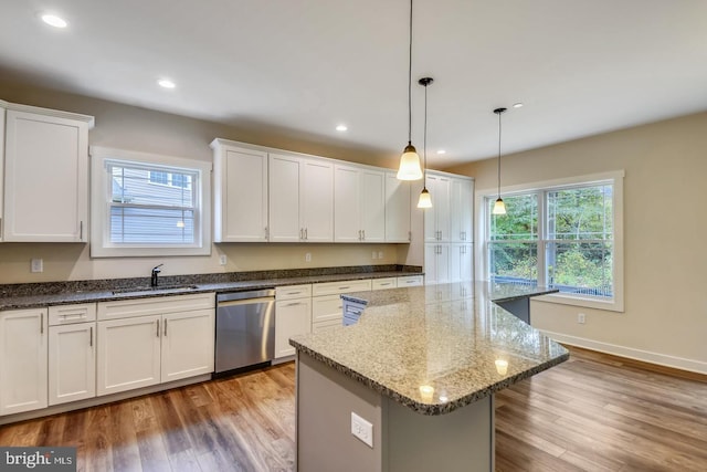 kitchen with sink, white cabinetry, hanging light fixtures, hardwood / wood-style floors, and stainless steel dishwasher