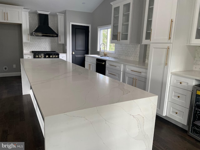 kitchen featuring white cabinets, a kitchen island, wall chimney range hood, light stone countertops, and dark hardwood / wood-style flooring