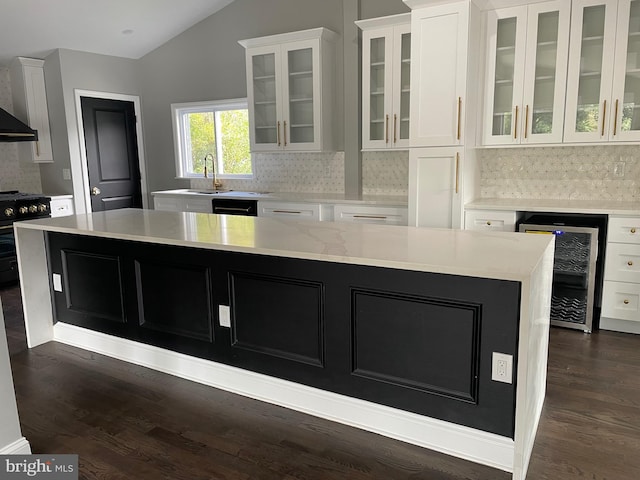 kitchen with beverage cooler, a kitchen island, dark wood-type flooring, high end stainless steel range, and white cabinetry