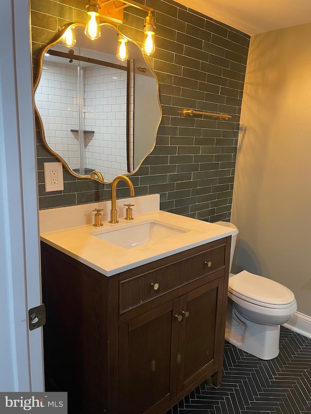 bathroom featuring toilet, tile patterned floors, tile walls, backsplash, and vanity