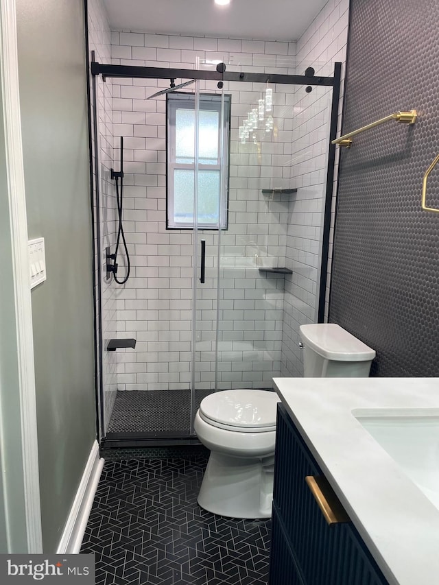 bathroom featuring tile patterned flooring, vanity, walk in shower, and toilet