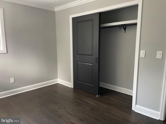 unfurnished bedroom featuring ornamental molding, a closet, and dark hardwood / wood-style floors