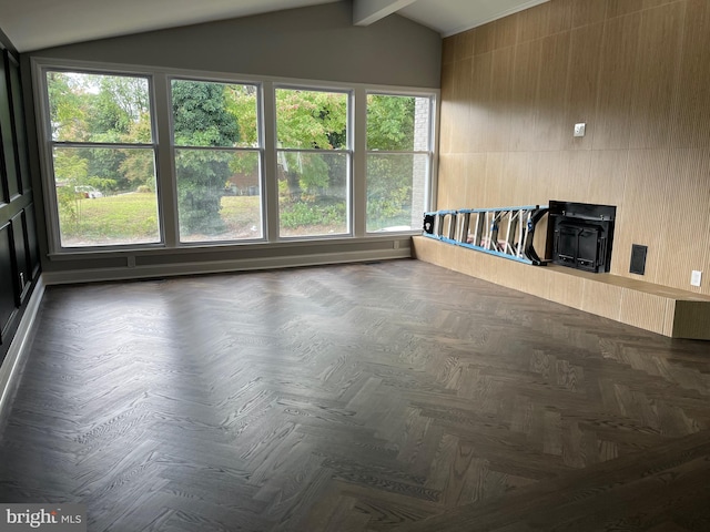 unfurnished living room featuring lofted ceiling with beams, dark parquet floors, and a wood stove