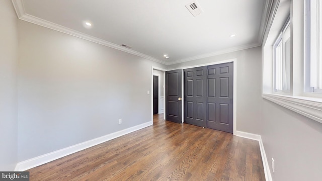 unfurnished bedroom featuring a closet, crown molding, and dark hardwood / wood-style flooring