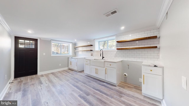 kitchen featuring tasteful backsplash, sink, light hardwood / wood-style floors, white cabinetry, and ornamental molding